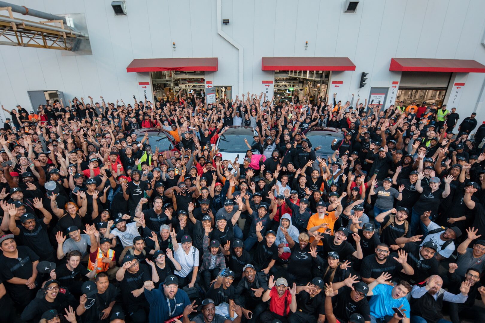 Фотография команды, празднующих достижения целей производства электромобилей Tesla